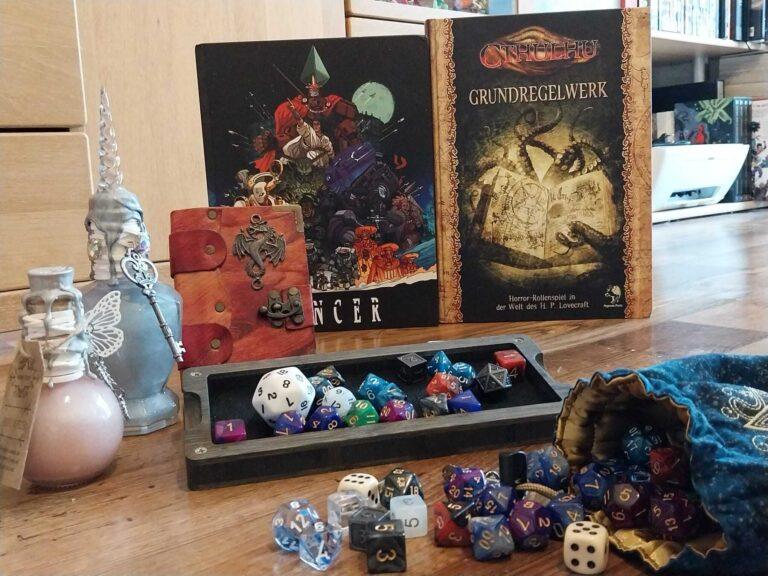 Ganz viel TTRPG Zubehör und 2 Regelbücher im Hintergrund